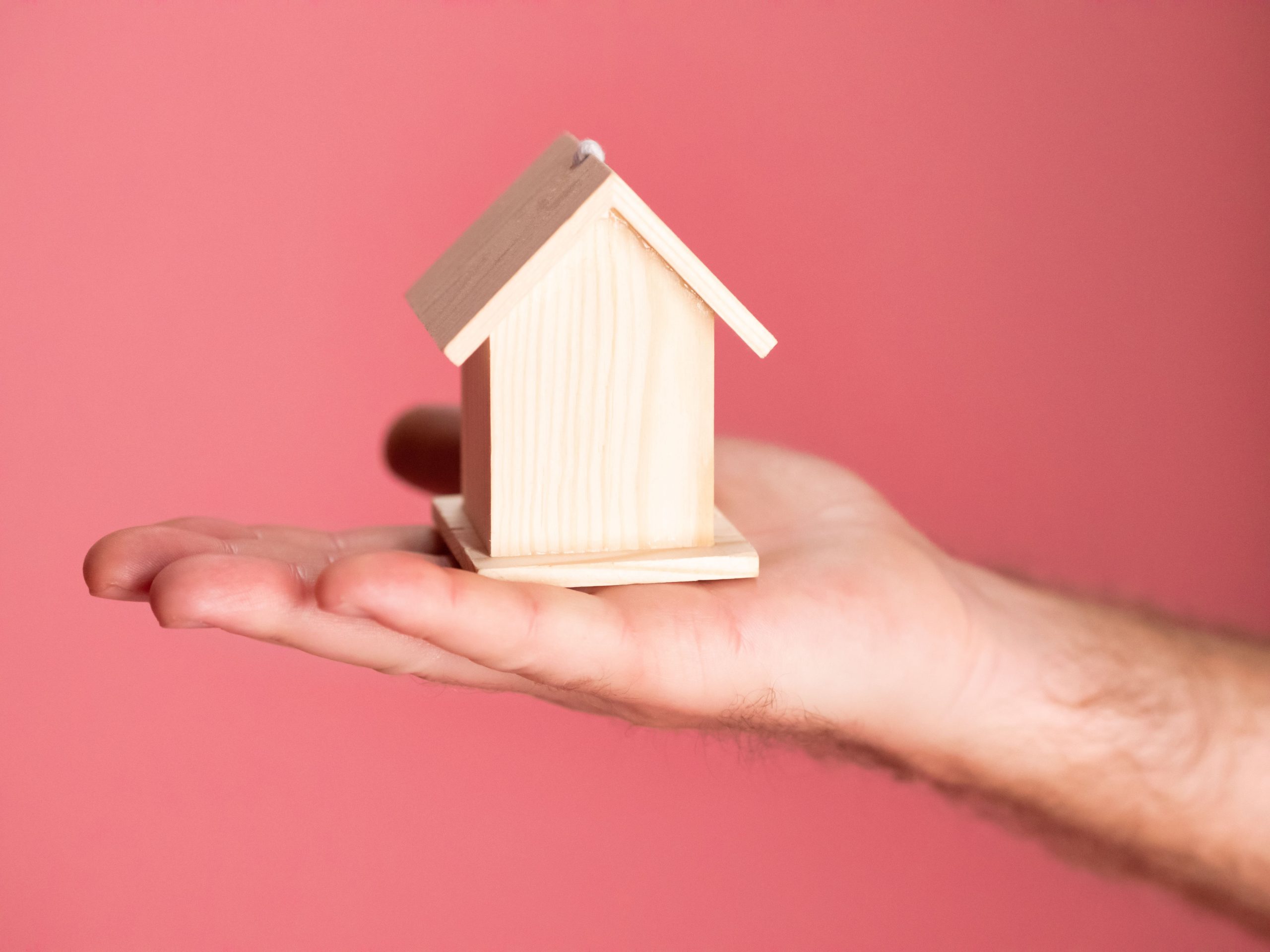 Maquette maison main concept immobilier fond rose