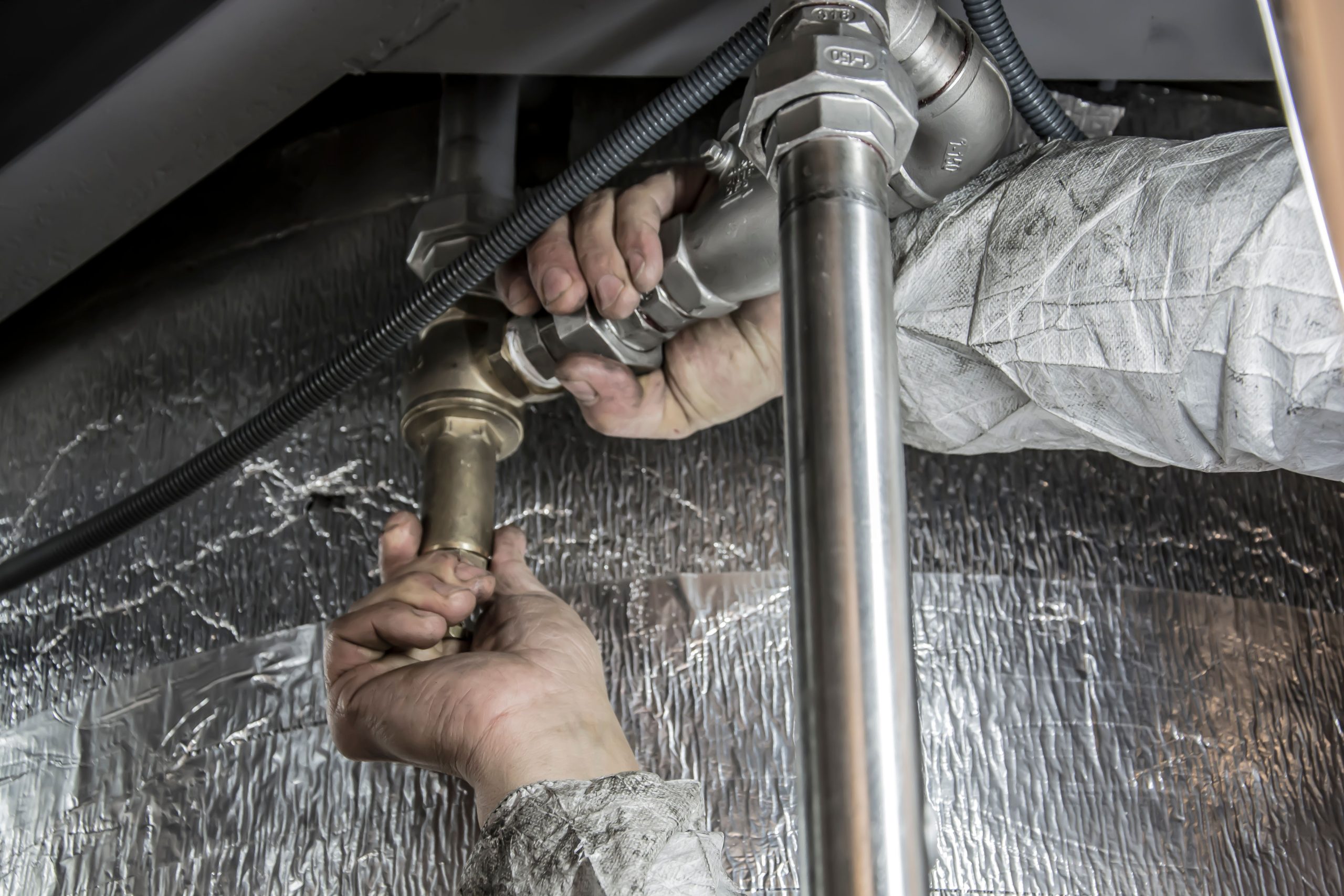 Mains de plombier installant tuyaux acier intérieur