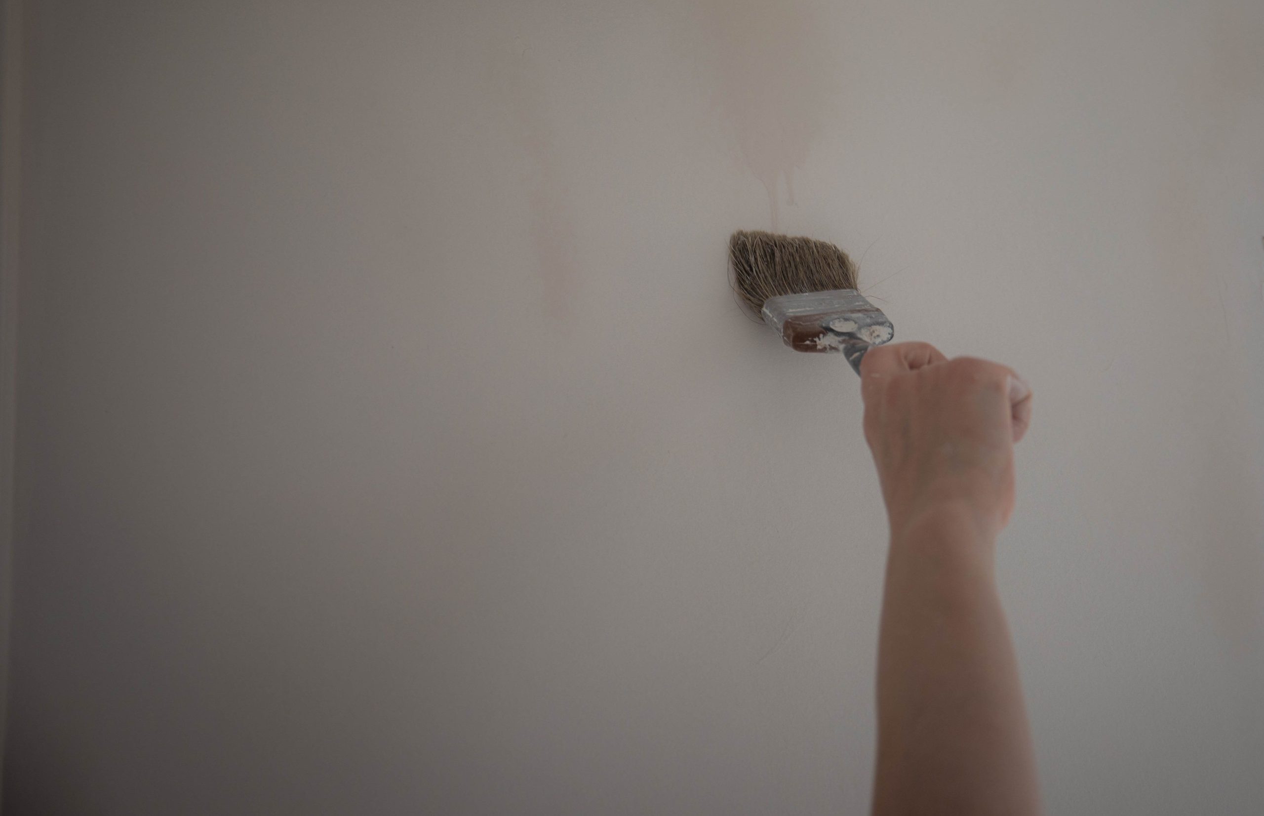 Pinceau appliquant peinture sur mur blanc