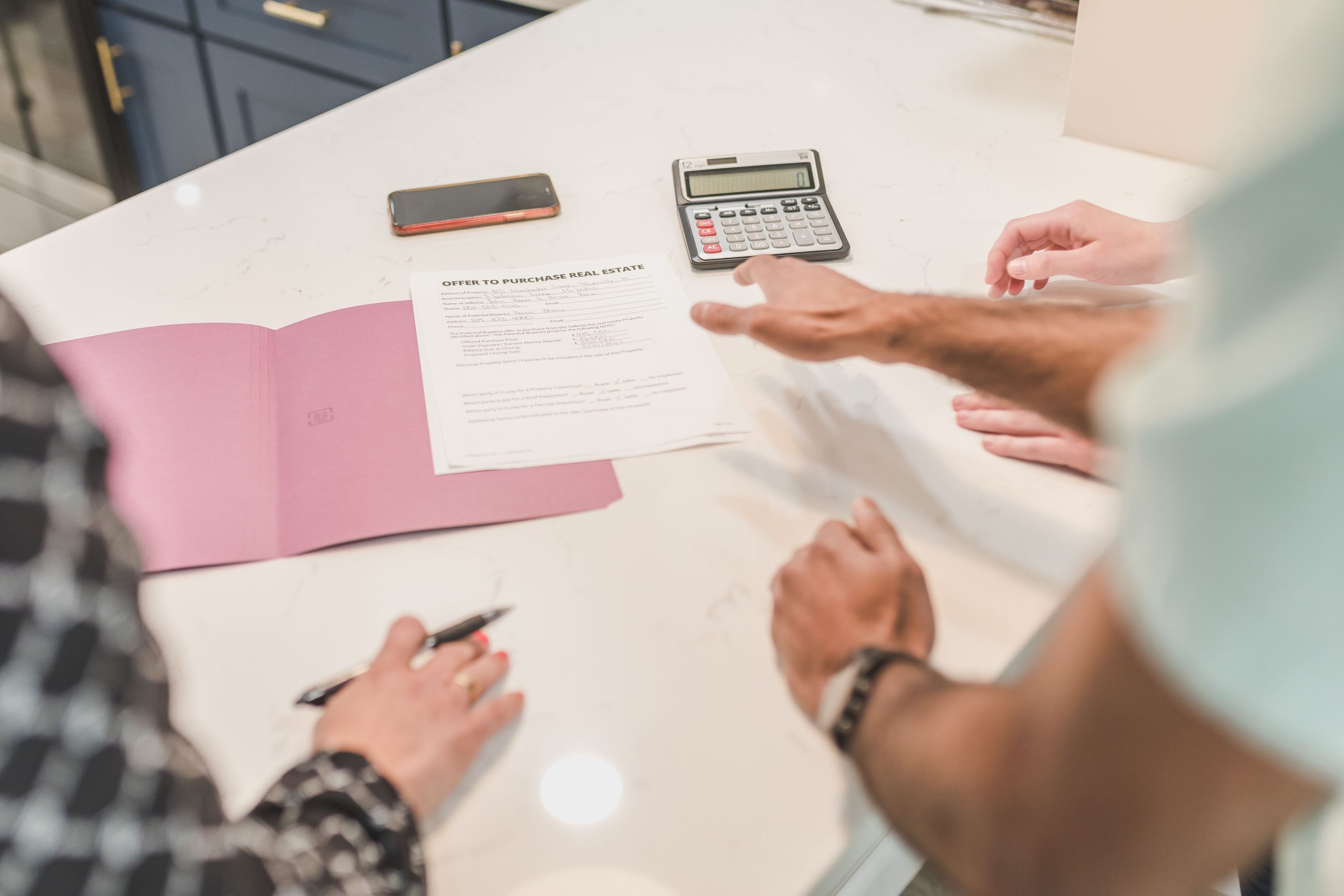 Mains examinant documents immobiliers avec calculatrice
