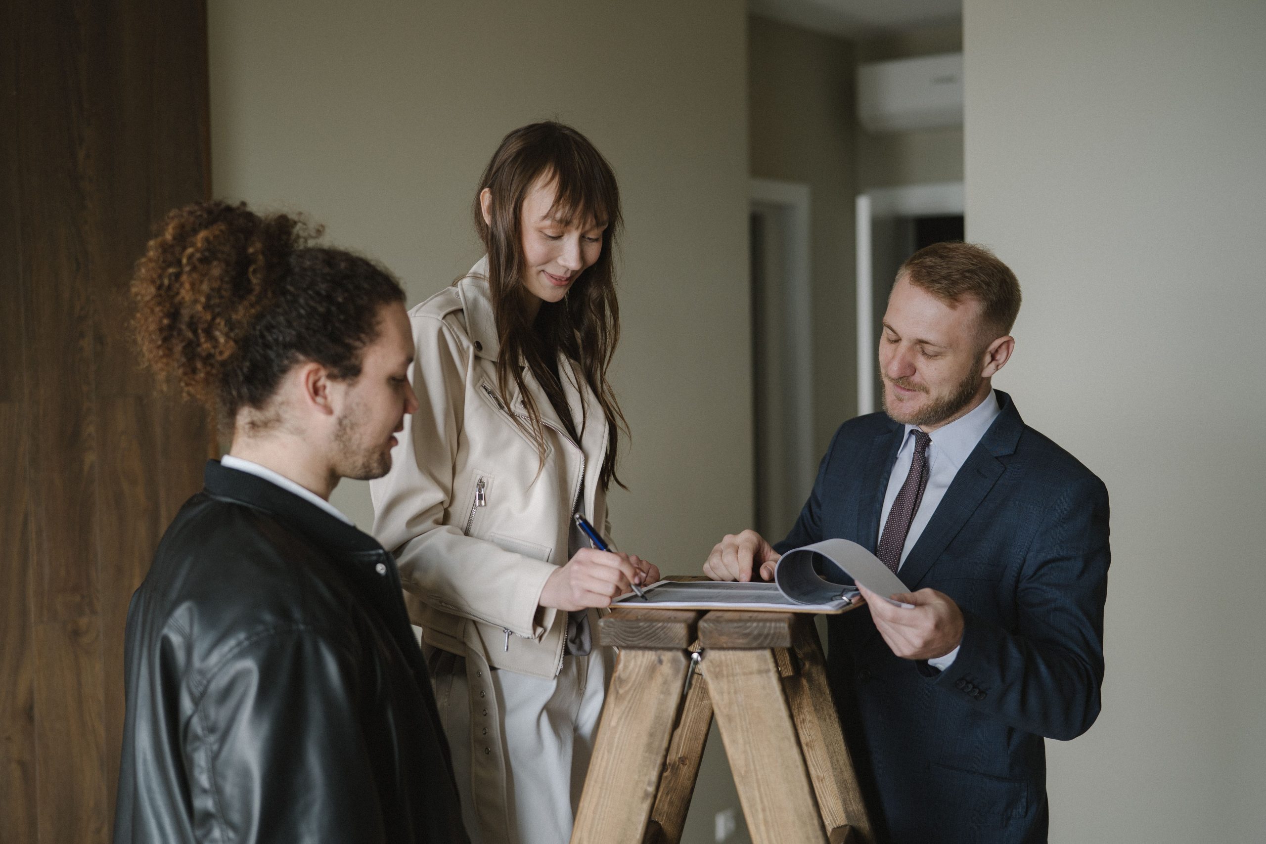 Couple signant documents immobiliers avec agent