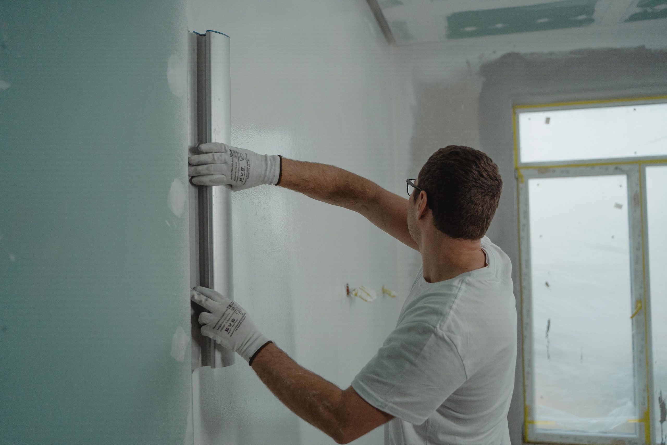 Homme utilisant règle métal rénovation mur